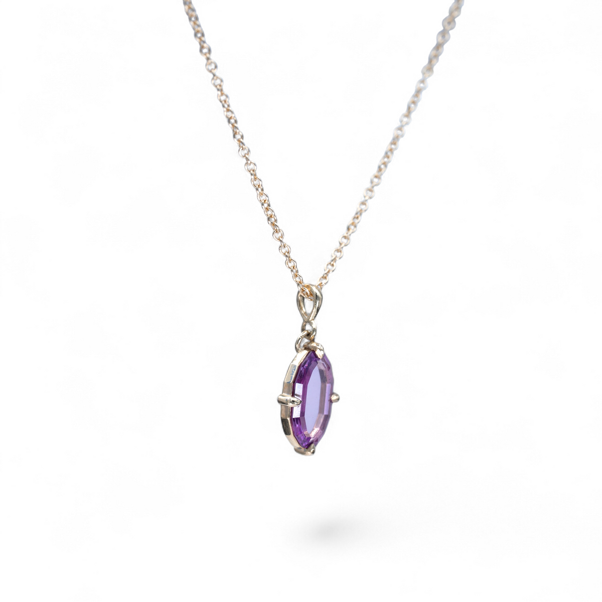 Side view of the Rosewater pink portrait-cut sapphire pendant showing the claw prongs and faceted edge