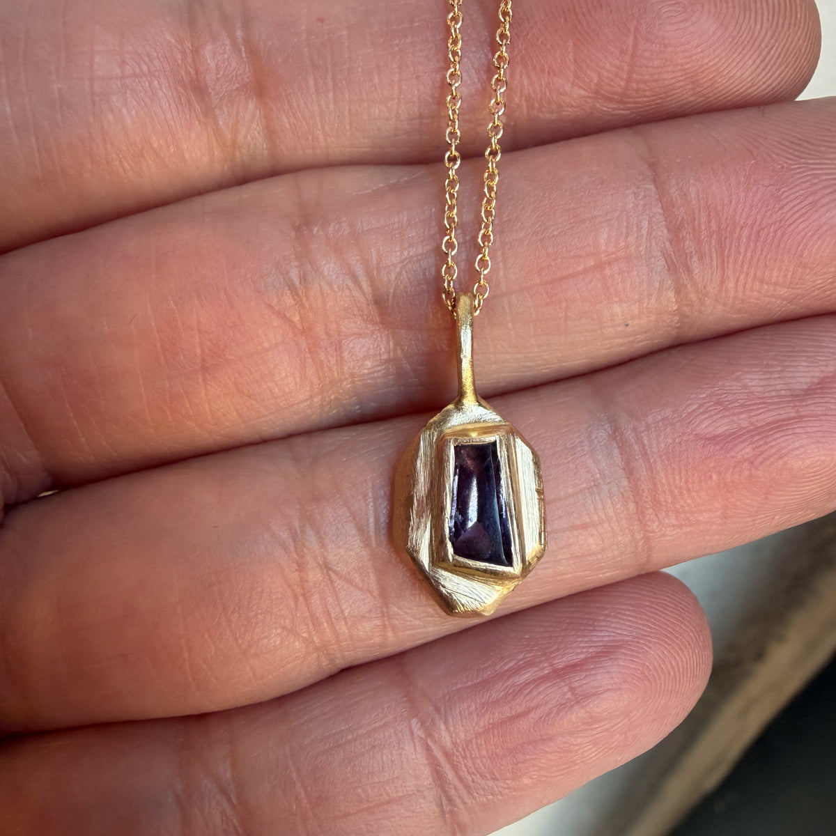 Violet Shard purple sapphire charm in 14k yellow gold, held in the fingers to show its size