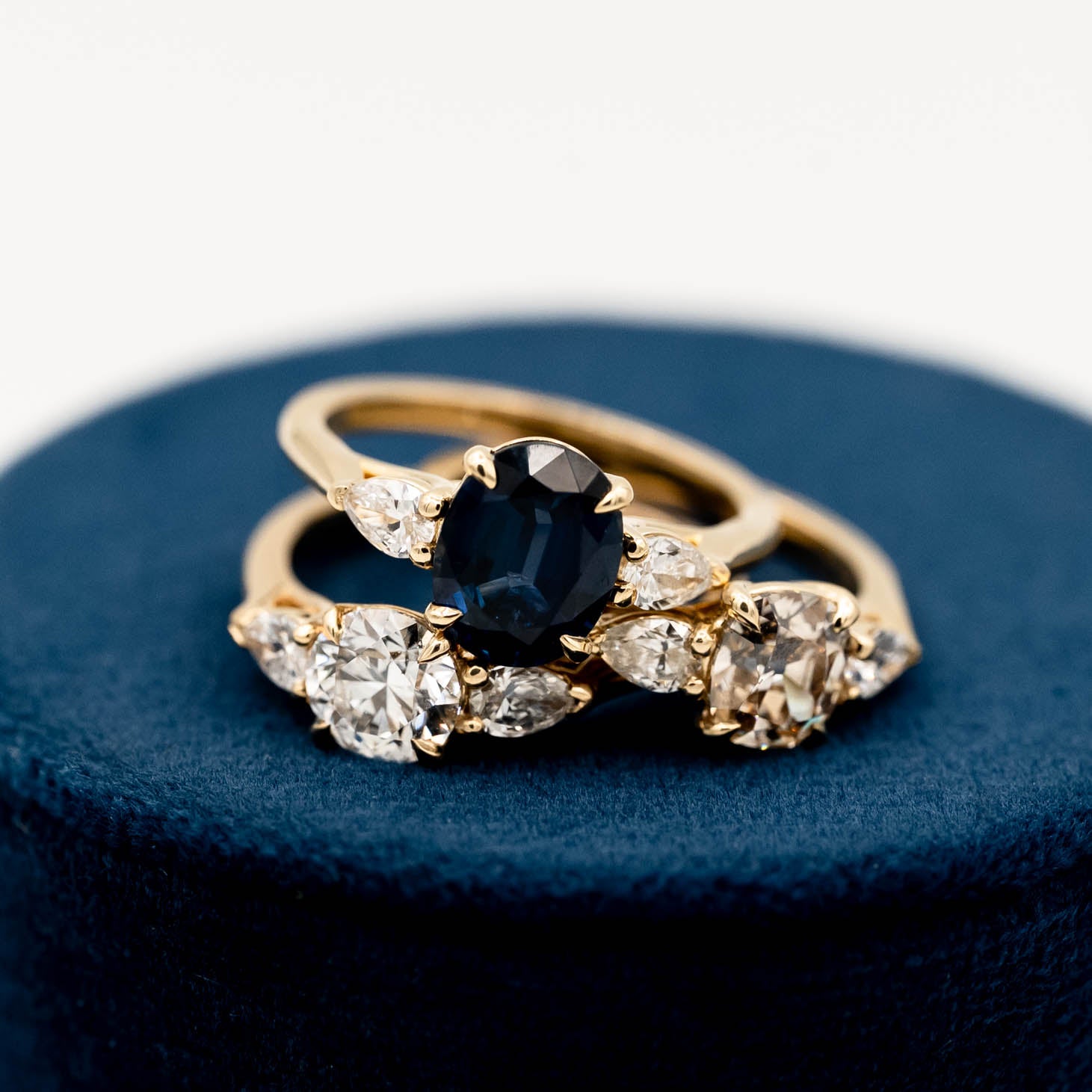 Collection three Acacia style 3-stone engagement rings with pear-shaped side stones, set in elegant trellis settings and 14k yellow gold bands. Ethically made jewelry in Seattle, WA.