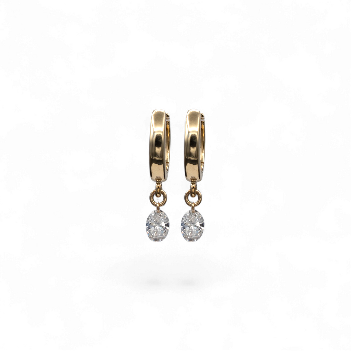 Stórica Studio Nereid Drops featuring oval lab-grown diamonds dangling from 14k yellow gold hinged huggie earrings.