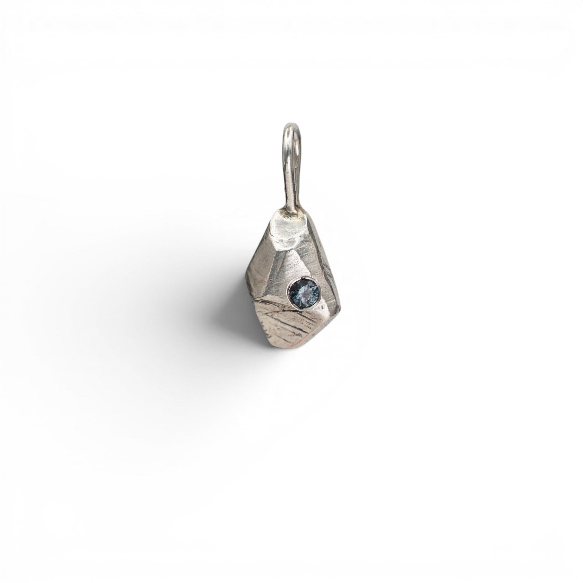 Stórica Studio sterling silver pendant with raw molten texture and a small faceted color-changing garnet stone.