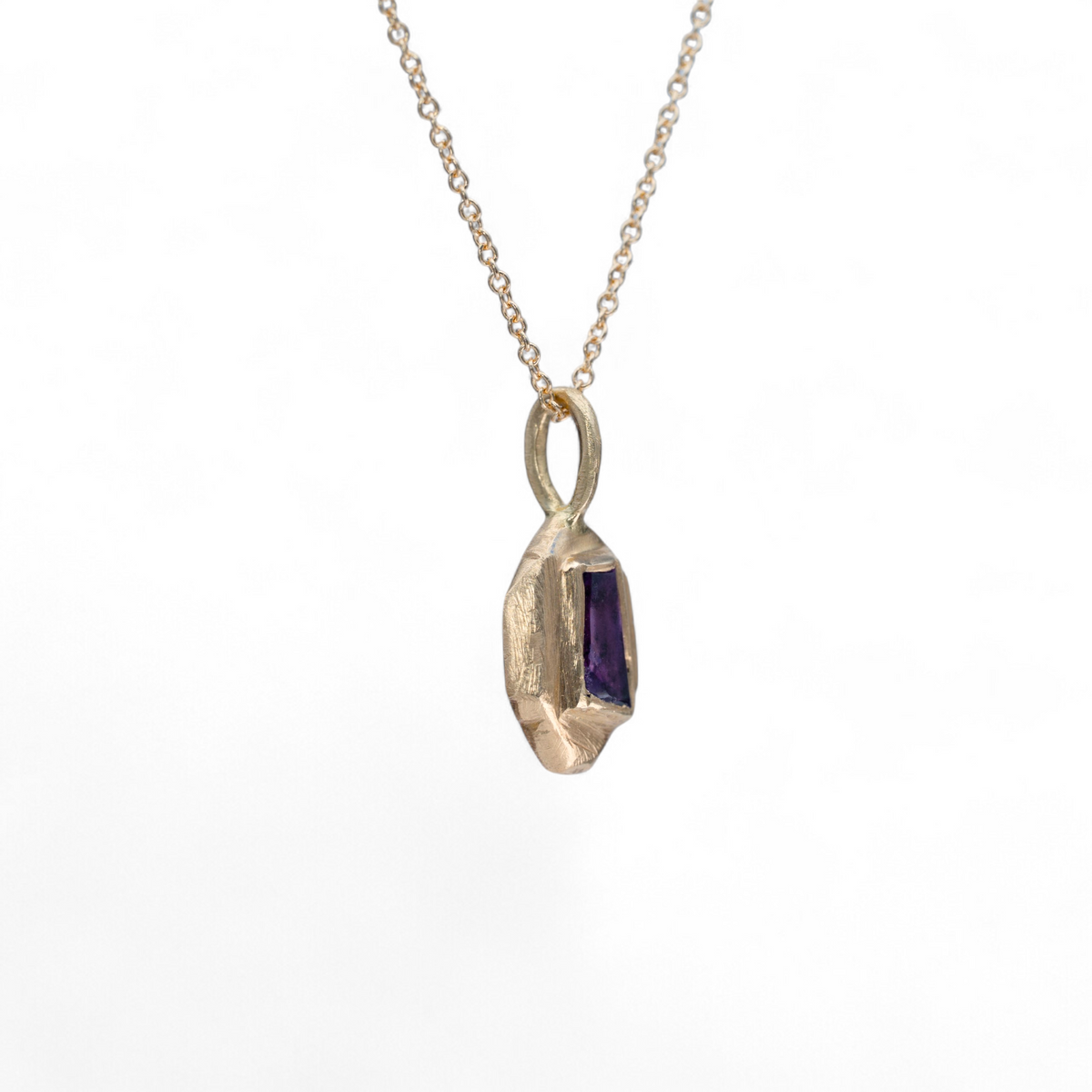 Stórica Studio Violet Shard charm featuring a tapered purple sapphire baguette set in hand-carved 14k yellow gold.