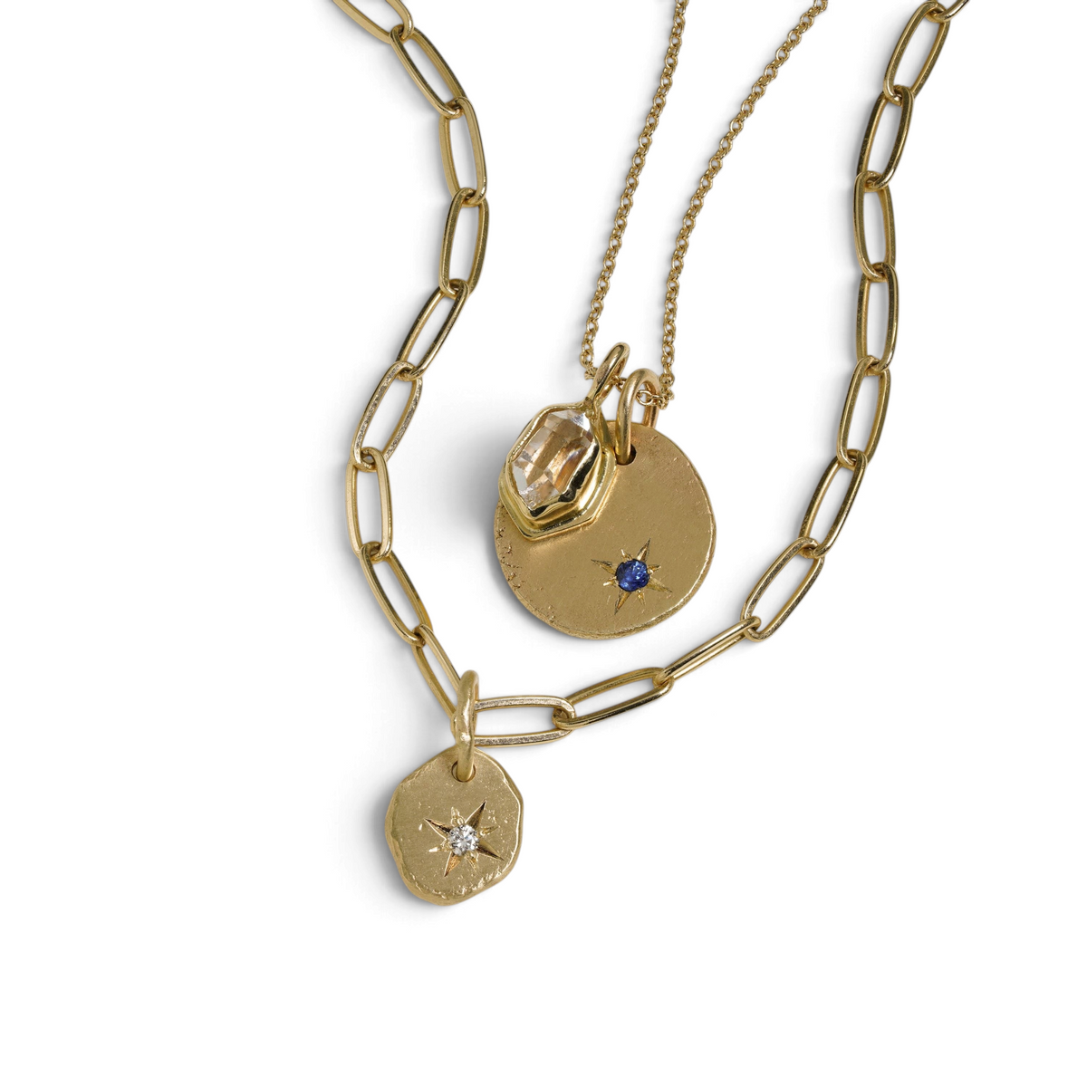 Stórica Studio Celestial Relic charms in gold with star-set gemstones on layered gold chain necklaces