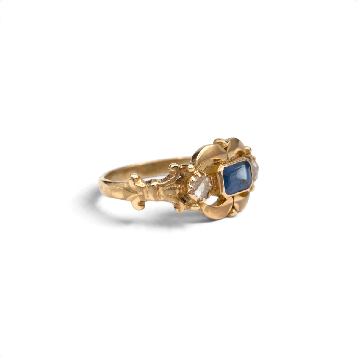 Stórica Studio Gentian antique sapphire ring showing sculpted gold leaf frame and fleur-de-lis shoulders
