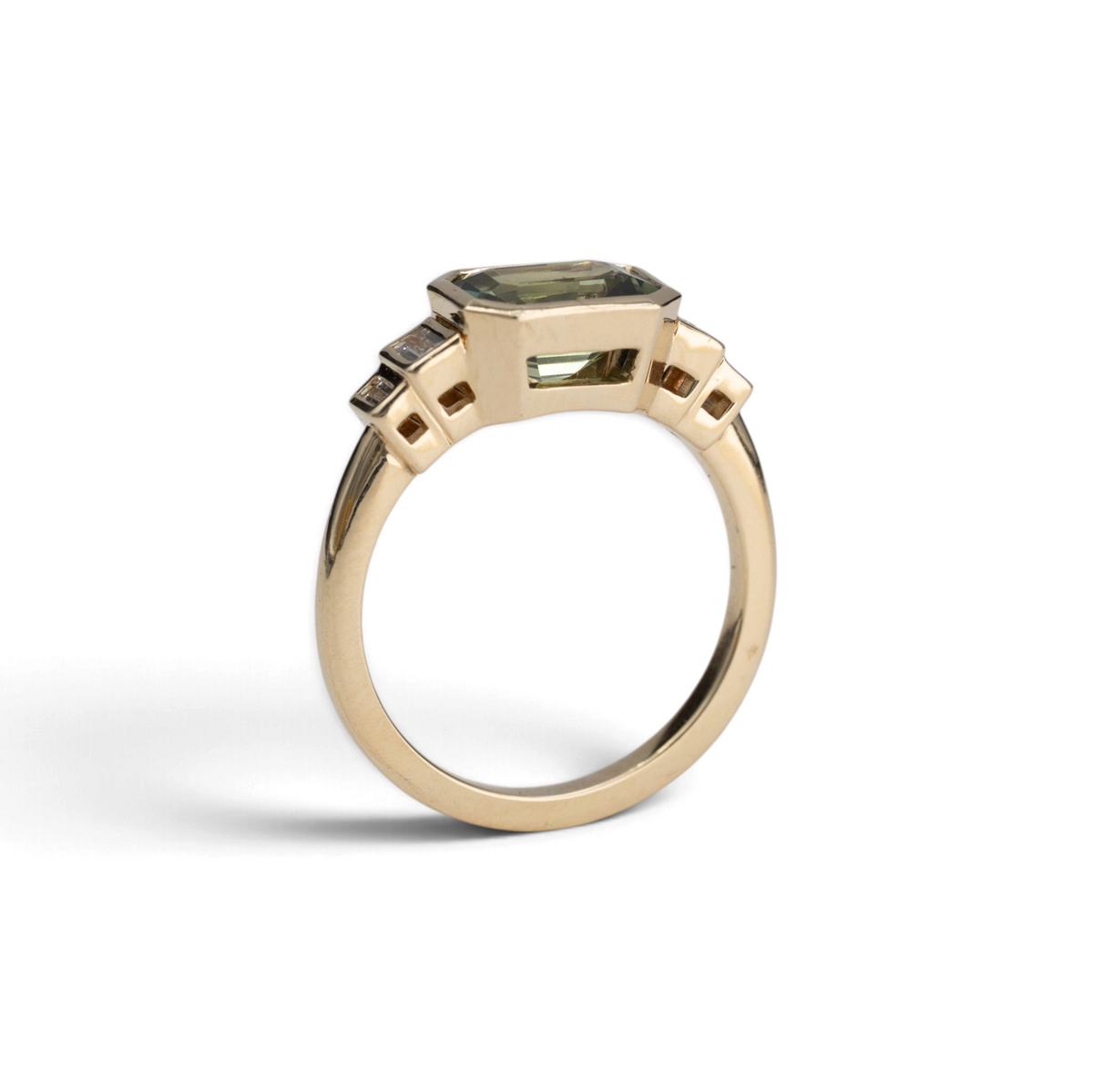 Stórica Studio 14k yellow gold ring featuring an emerald cut Australian sapphire in a bezel setting with baguette diamonds