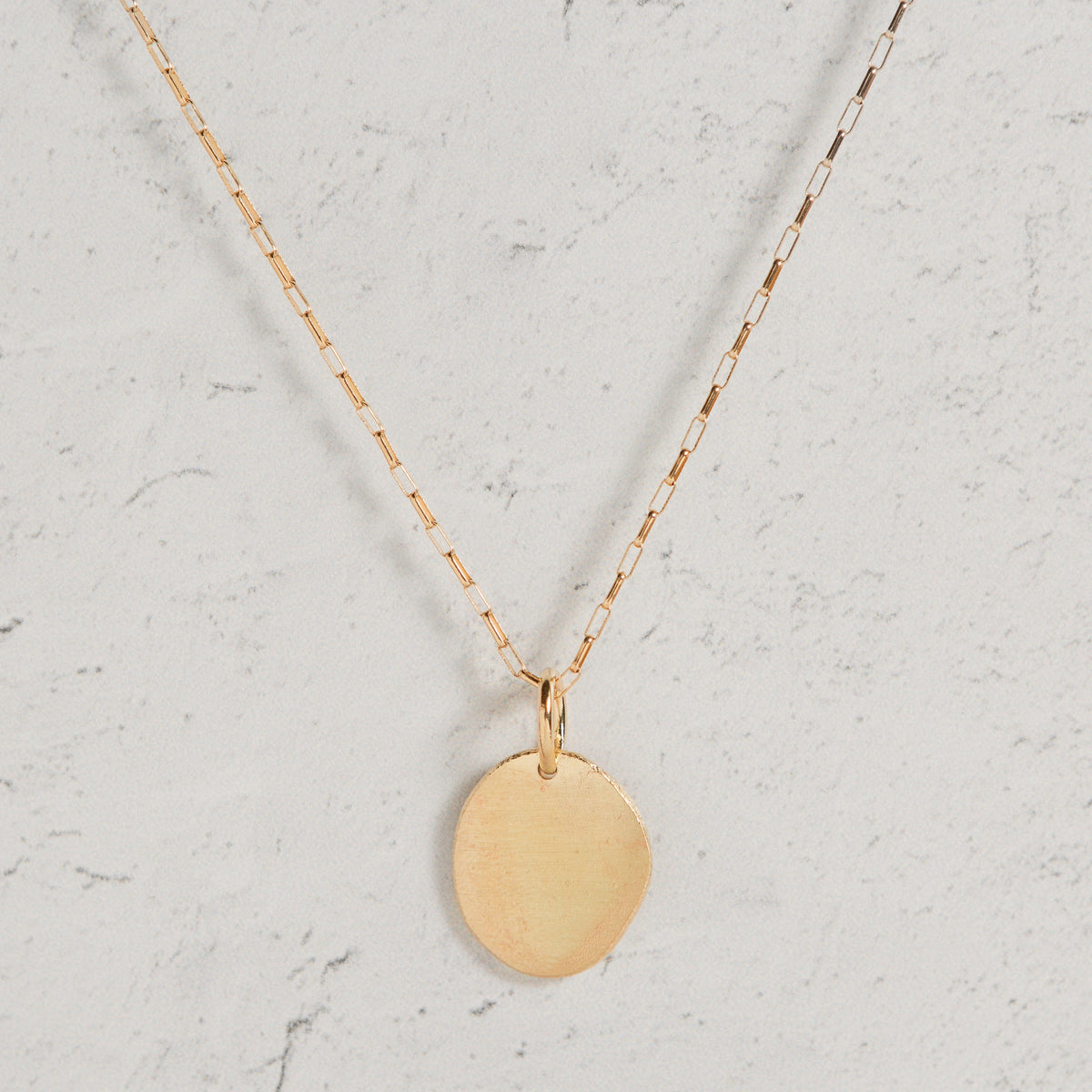Stórica Studio gold disc charm pendant on a delicate chain, handmade from reclaimed metal for custom engraving.