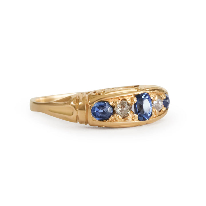 Gold ring with blue sapphires and diamonds on a white background