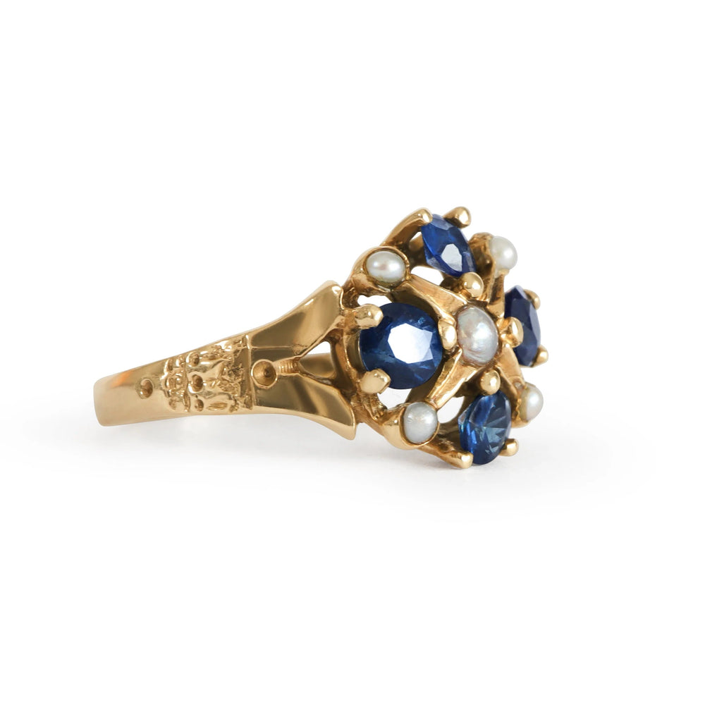 Gold ring with blue sapphires and pearls on a white background