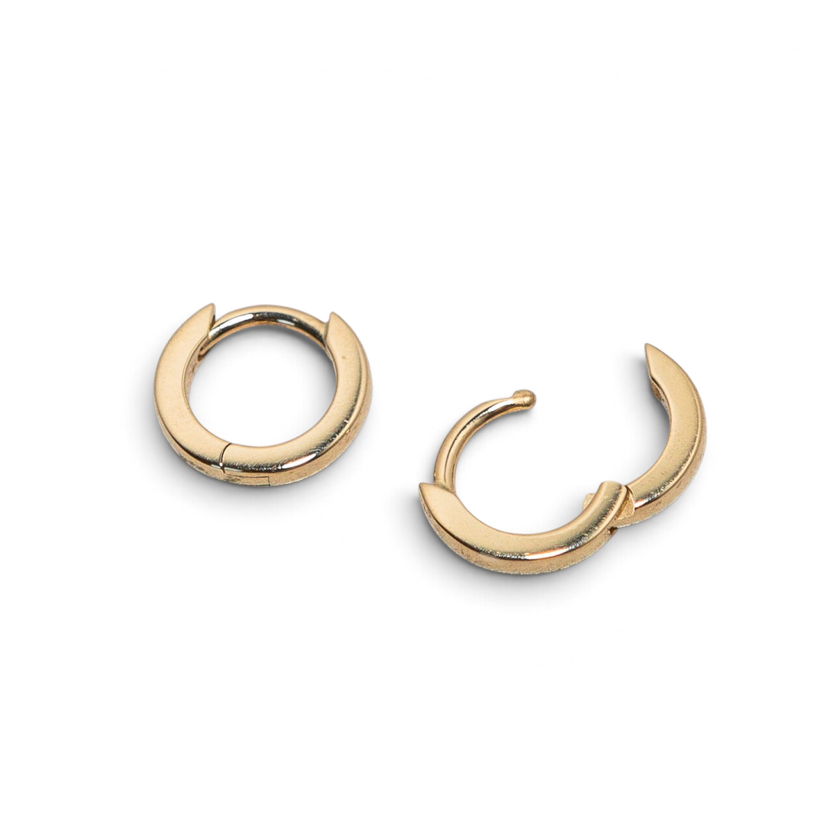 Stórica Studio Cove solid gold huggie hoop earrings with a polished finish and hinged click closure.