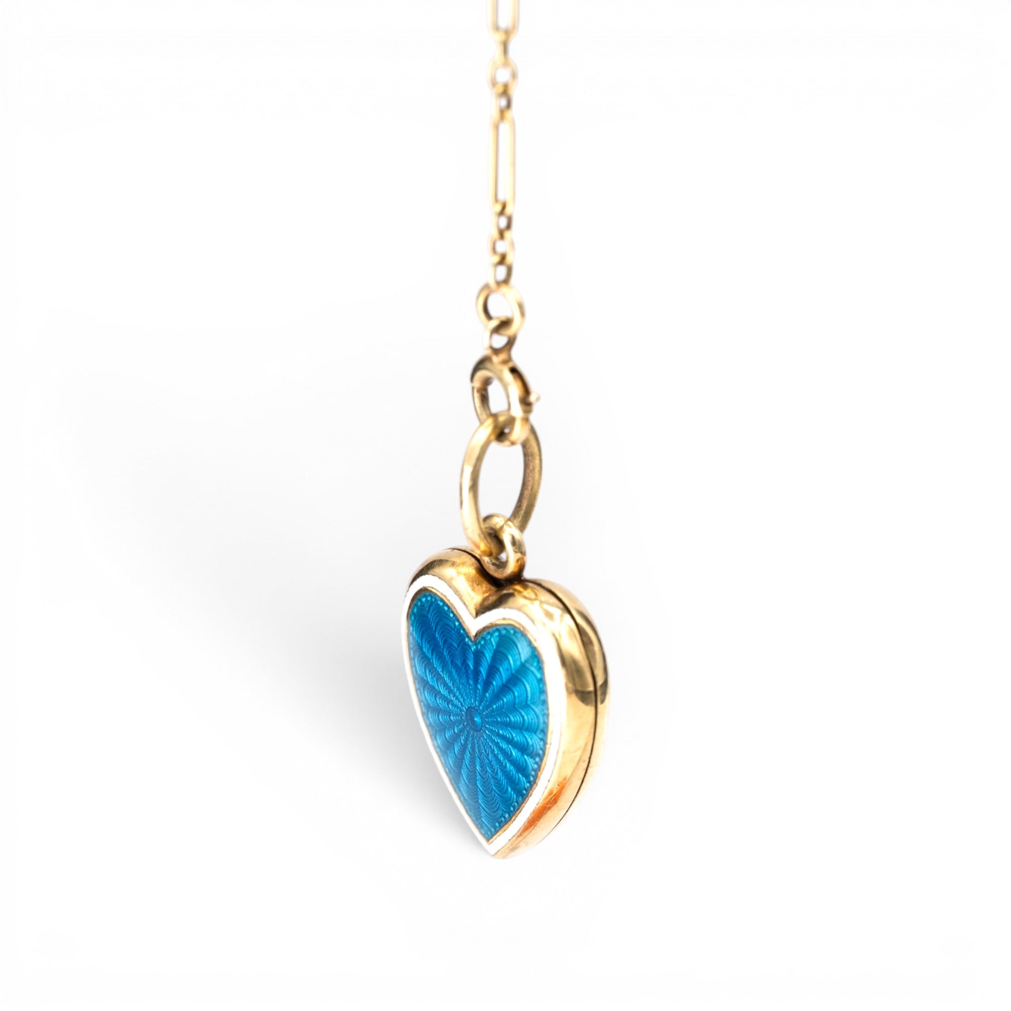 Stórica Studio antique 14K gold heart locket with blue guilloché enamel sunburst pattern on a delicate chain.