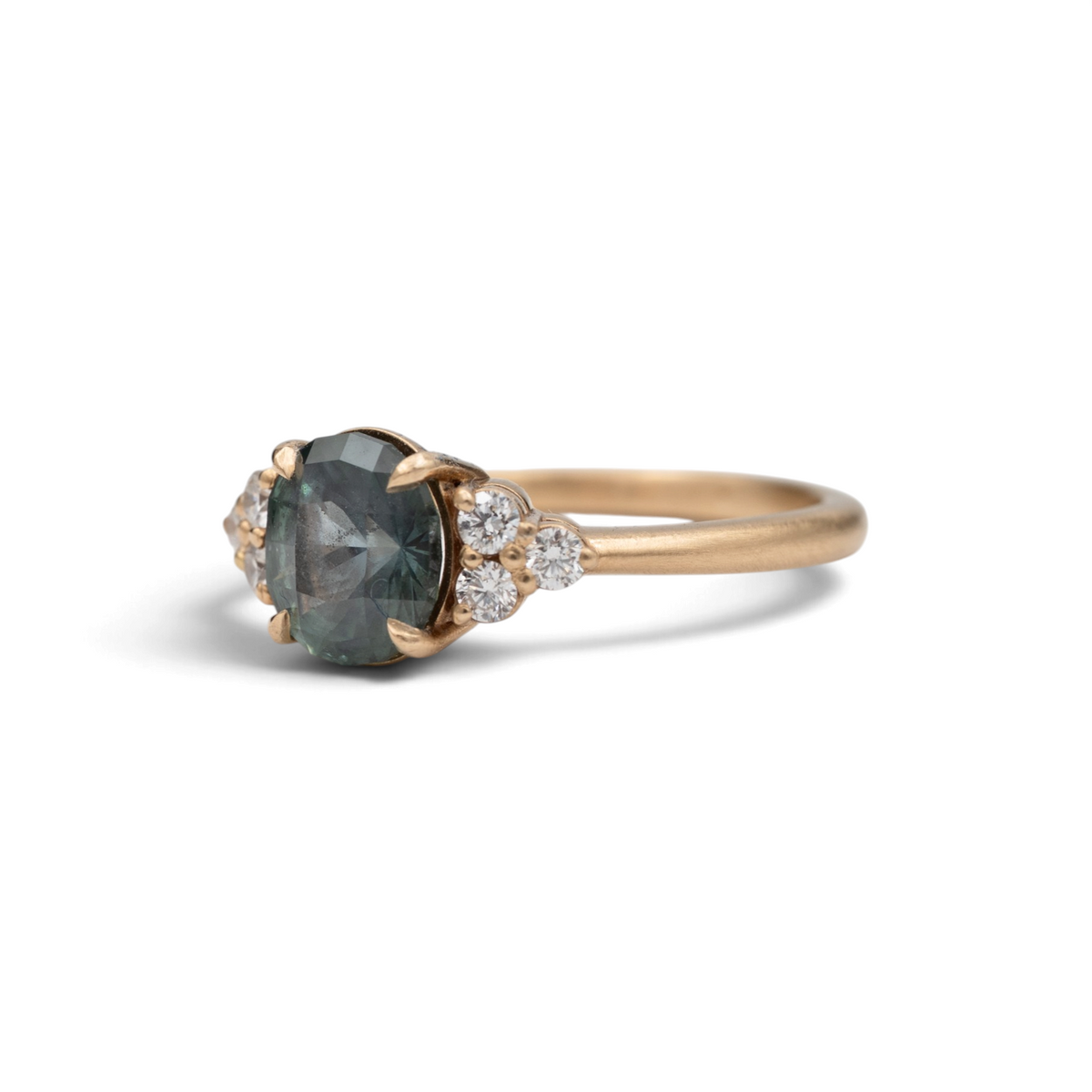 Stórica Studio The Holly ring featuring a 2.06ct oval Montana sapphire and round diamond side stones in 18k gold.