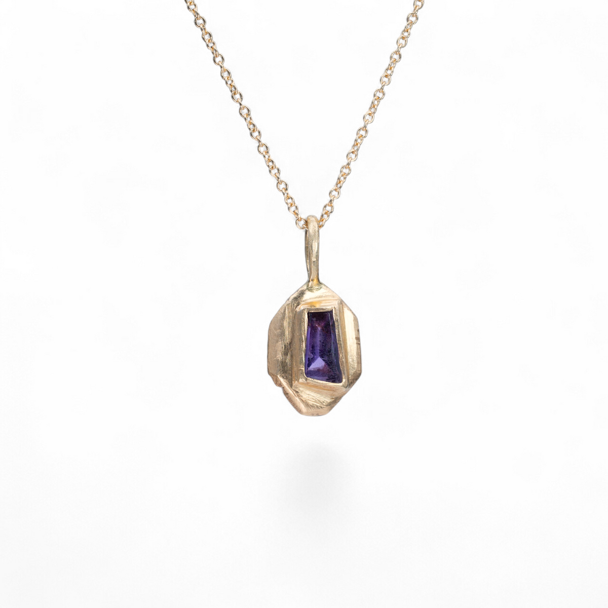 Stórica Studio Violet Shard charm featuring a purple sapphire baguette set in hand-carved 14k yellow gold.